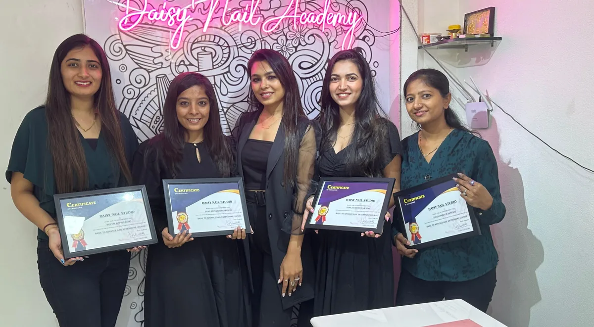 Daisy Nail Academy students holding their certificates in the training studio