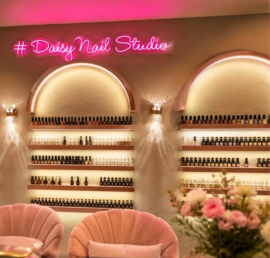 The arched, backlit polish wall and pink neon sign inside Daisy Nail Studio Ranip