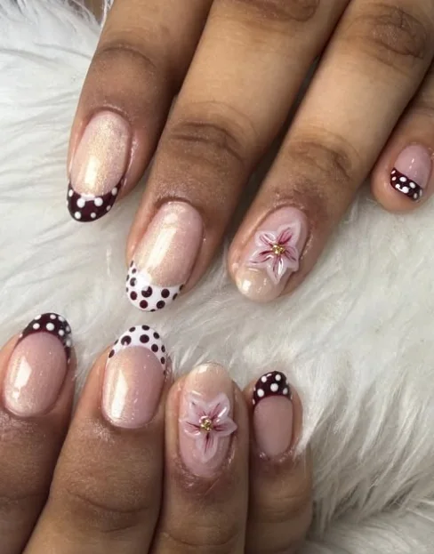 Pearlescent nude nails with cocoa polka-dot French tips and sculpted 3D plumeria accents